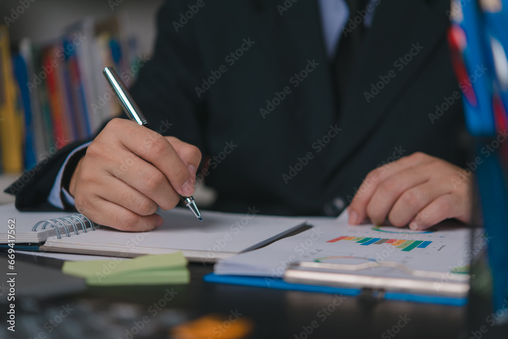 Male hand writing notes report marketing charts and financial graph data.