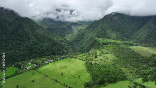 Lush green agricultural fields in rural community in the mountains of Ecuador on edge of canyon - Dynamic aerial drone video