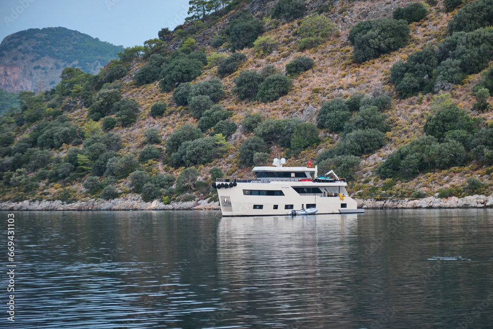 Beautiful yachts near a steep rocky coast at sunset. Beautiful yachts near a steep rocky coast at sunset.