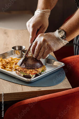 The chef cuts a burger with a knife. A close-up view