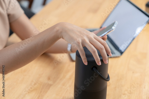 Modern Technology Concept. Young woman use portable speaker at home.