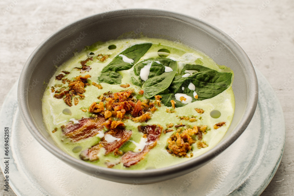 Spinach cream soup with bacon and crackers in a restaurant on the table
