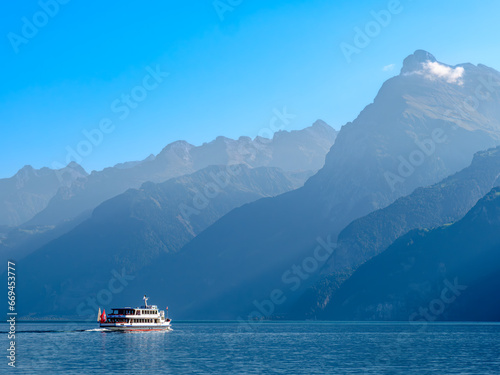 Outlines of the mountains by the swiss Lake Urnersee - Lake Luzerne - in the daytime hazy light. Tourist ship on the lake. © Taljat