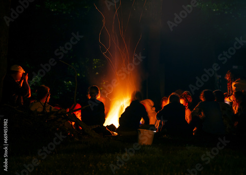 People around a bonfire at night. Figure silhouettes. Unrecognizable. Warm atmosphere.