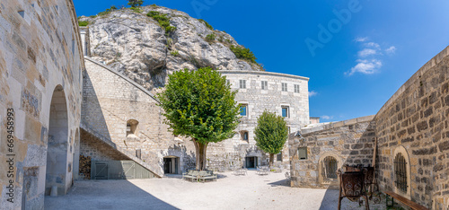 Fort l'Écluse, France - 09 01 2021: View of the upper fort courtyard with trees and the rock behind. photo