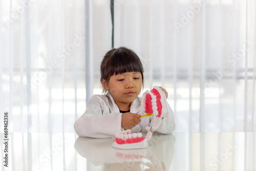 Little cute funny girl holding tooth jaw, toothbrush. Kid training oral hygiene. Child learning brushing, cleaning teeth. Prevention of caries in children. children dentistry. dental care kids