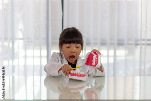 Little cute funny girl holding tooth jaw, toothbrush. Kid training oral hygiene. Child learning brushing, cleaning teeth. Prevention of caries in children. children dentistry. dental care kids