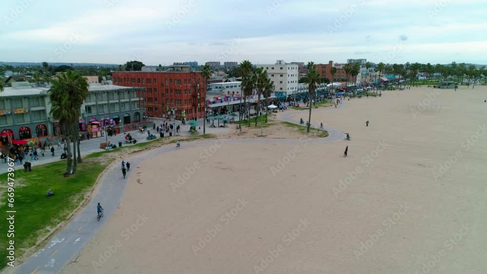 Aerial Forward Shot Of People On Footpath At Beach Near Buildings In Neighborhood Against Sky - Los Angeles, California Aerial Forward Shot Of People On Footpath At Beach Near Buildings In Neighborhood Against Sky - Los Angeles, California