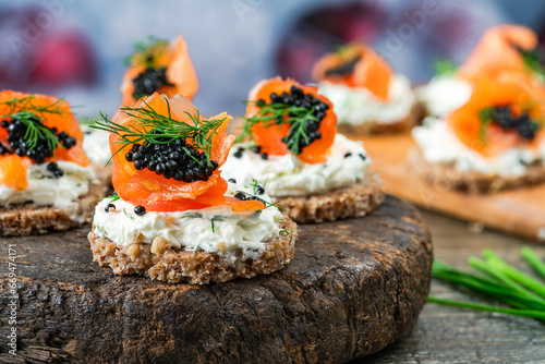 Fototapeta Cocktail canapes with smoked salmon, cream cheese and caviar on rye bread - gourmet party food