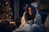 Beautiful brunette latina single young woman smile happy and holding a cup of coffee in her cozy living room with copy space, wearing a warm dressing robe, decorated Christmas tree in background