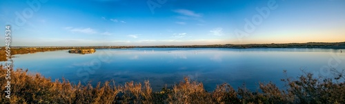 Panoramic of one of the salt lagoons of the Salinas de San Pedro del Pinatar Regional Park, with beautiful daylight and flamingos in the water