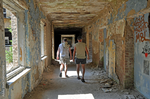 Dwie osoby w wakacyjnym ubiorze spacerują korytarzem zrujnowanego budynku kasyna wojskowego w Bornem - Sulinowie. Polska.  photo