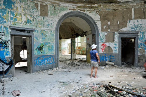 Kobieta ubrana wakacyjnie ogląda duże pomieszczenie zrujnowanego budynku kasyna wojskowego w Bornem - Sulinowie, Polska.  photo