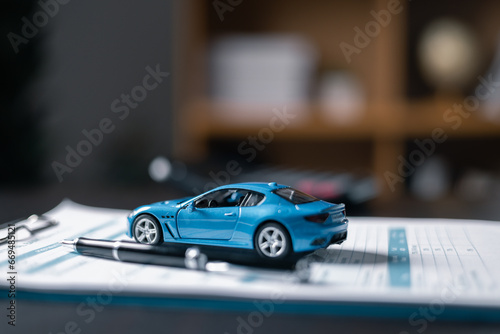 Black ballpoint pen, calculator and blue car on paper form, Blur with office background, out of focus, Protecting and after-sales care concept. offering financial and insurance service.