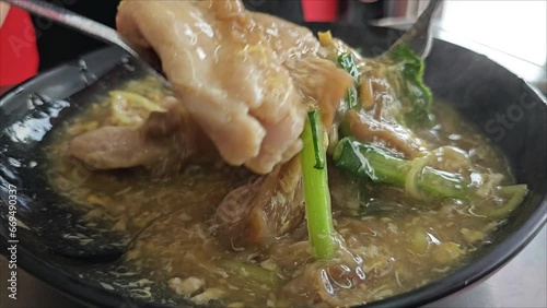 Clip of mixing and topping the large noodles with fresh chilies and pepper powder. photo