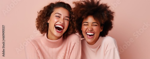 African American and Caucasian girlfriends laugh cheerfully while taking a photo together. Cheerful best friends laugh together posing for photo. Young women of different races support each other