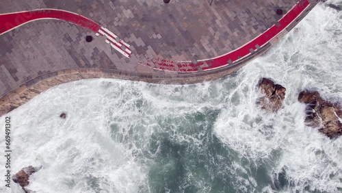 Aerial drone top down view of stormy waves hitting the promenade in Cascais, Portugal photo