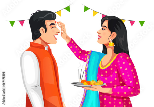 Indian woman is giving blessings to the brother by putting tika on his forehead. Both wearing traditional ethnic clothes. Celebrating Indian festival Bhai dooj