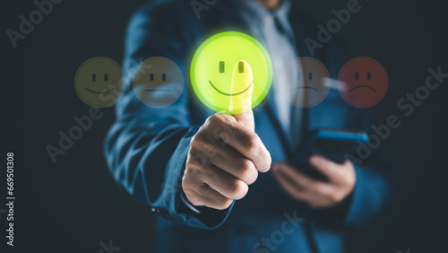 Close-up customer satisfaction rating concept. Person thumb up on smile face to give best score survey or feedback service, holding smart phone by hand. Wireless technology and mobile application