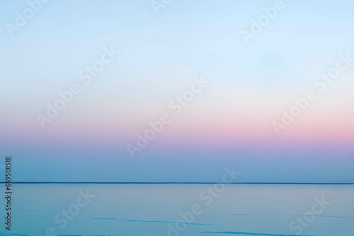 夕暮れの穏やか薄いブルーとピンクが混ざるパステルカラーの海と空の海岸線