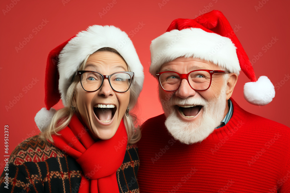 old retired couple in christmas hats having fun in front of red background. Funny and cool image for creative christmas ad campaign old retired couple in christmas hats having fun in front of red background. Funny and cool image for creative christmas ad campaign