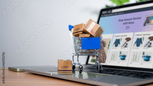 Shopping cart and product boxes placed on laptop computer represent online shopping concept, website, e-commerce, marketplace platform, technology, transportation, logistics and online payment concept photo