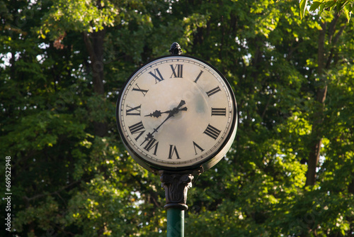 An old clock on a city street.Park area.