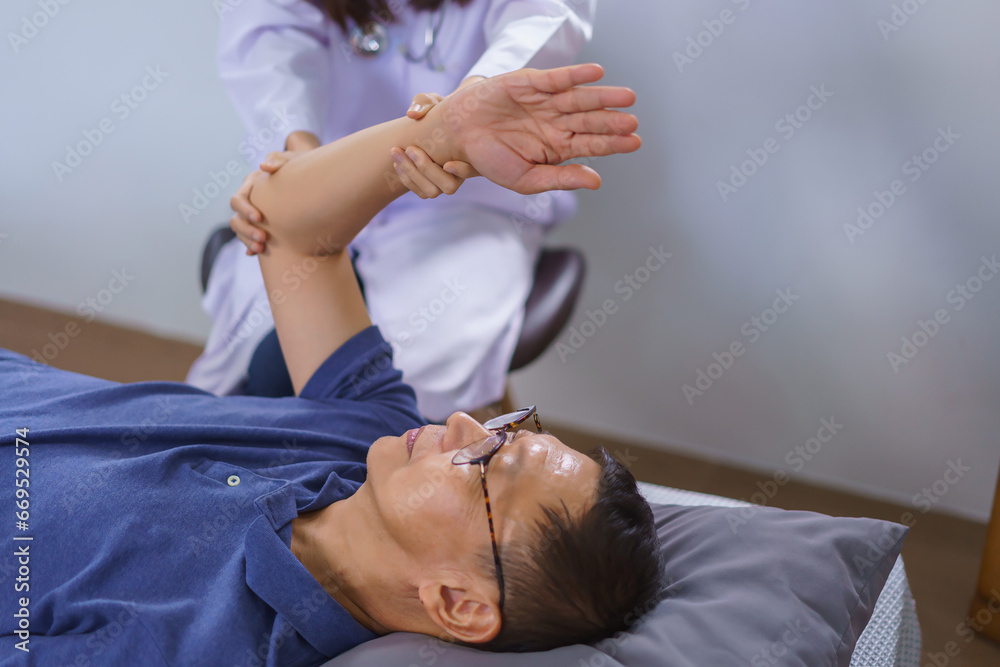 Healthy concept, Senior man lying on bed doing physiotherapy and stretching arm by woman caregiver