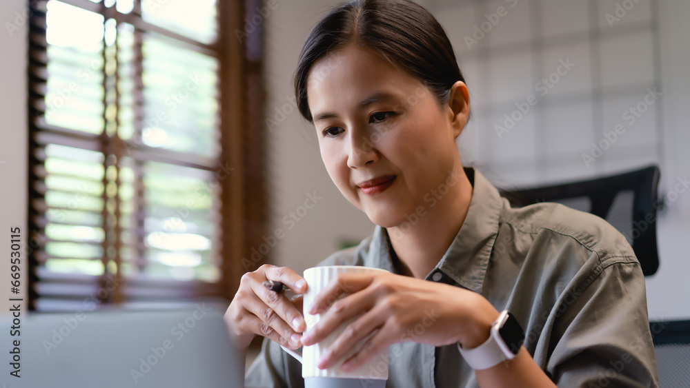 Casual business women read data on laptop and drink coffee while analysis about marketing strategy Casual business women read data on laptop and drink coffee while analysis about marketing strategy