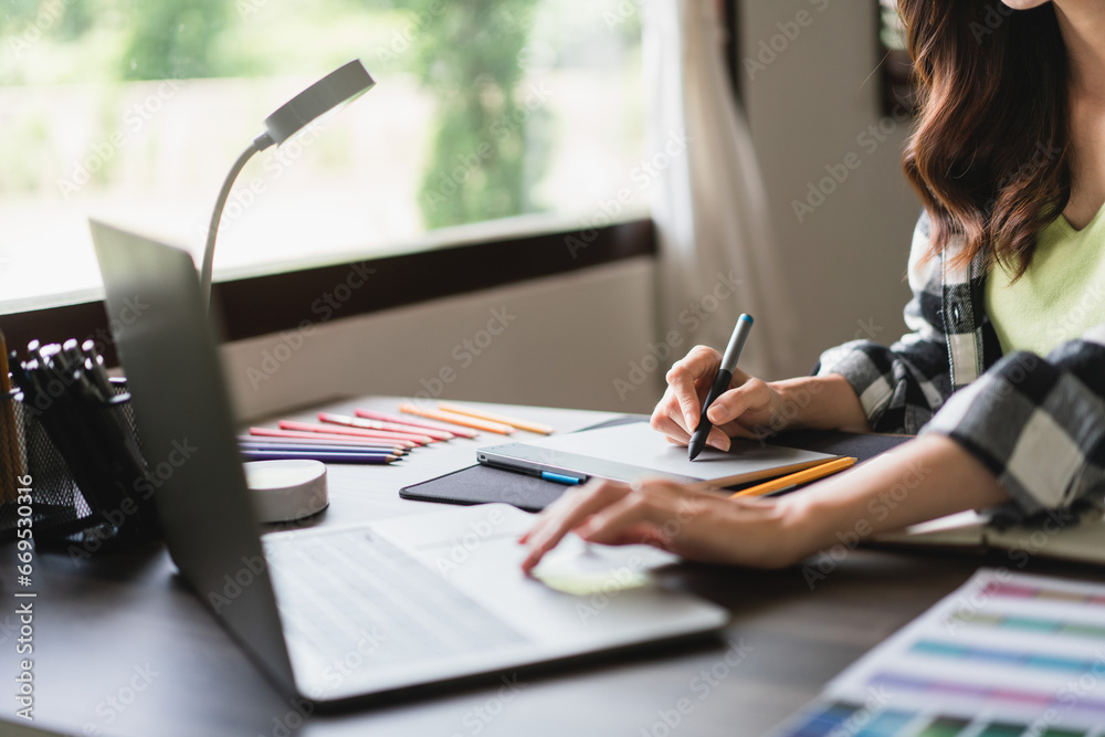 Female artist designer working on laptop to design and drawing logo brand on graphic tablet Female artist designer working on laptop to design and drawing logo brand on graphic tablet