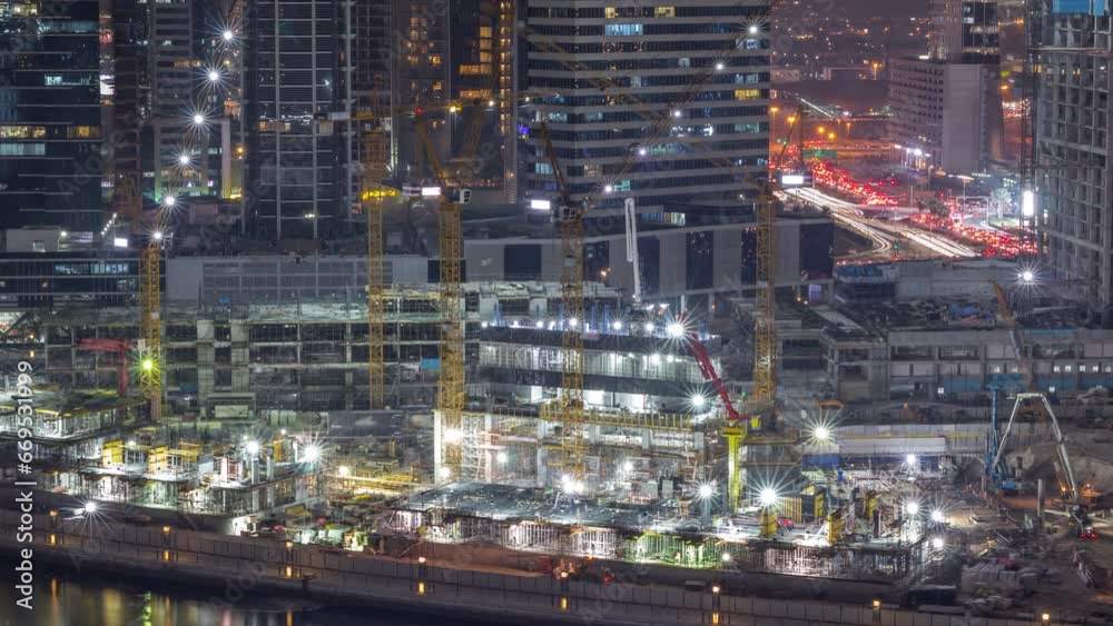 Large construction site with many working cranes night timelapse. Top aerial view of big development of residential and office district in Business bay, Dubai. Lights in illuminated towers and traffic Large construction site with many working cranes night timelapse. Top aerial view of big development of residential and office district in Business bay, Dubai. Lights in illuminated towers and traffic