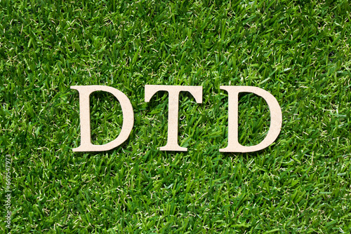 Wood alphabet letter in word DTD (Abbreviation of door to door, document type definition, depositor transaction declaration) on artificial green grass background photo