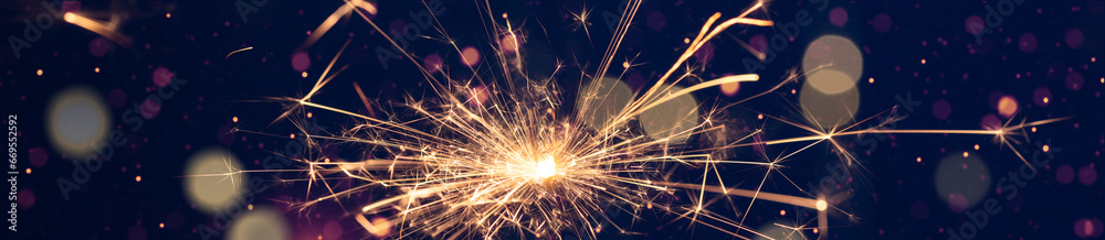 Burning sparkler with bokeh light on blue background. New year party background. New year sparkles. Burning sparkler with bokeh light on blue background. New year party background. New year sparkles.