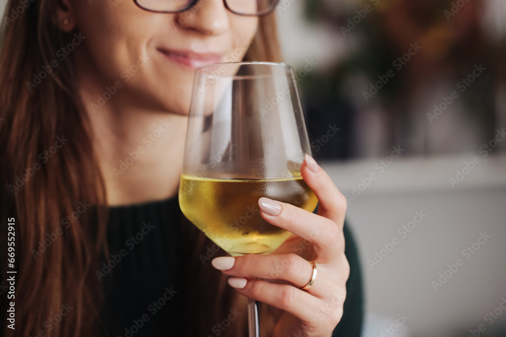 Woman drinking wine. White wine drinking. Wine glass in hand. Girl in woolen sweater. Cozy winter alcohol background. Female hand holding wine glass. Winter season clothing. Cute smile happy woman.