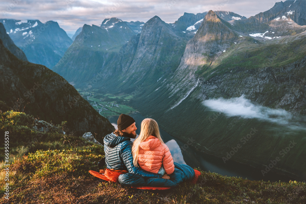 Couple in love hiking together romantic vacations with travel camping gear, Man and woman in sleeping bags enjoying mountains landscape outdoor family healthy lifestyle friends exploring Norway - obrazy, fototapety, plakaty 