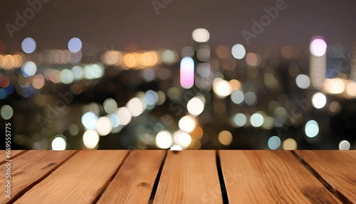 Empty wooden table top with on blurred building, tower at night.