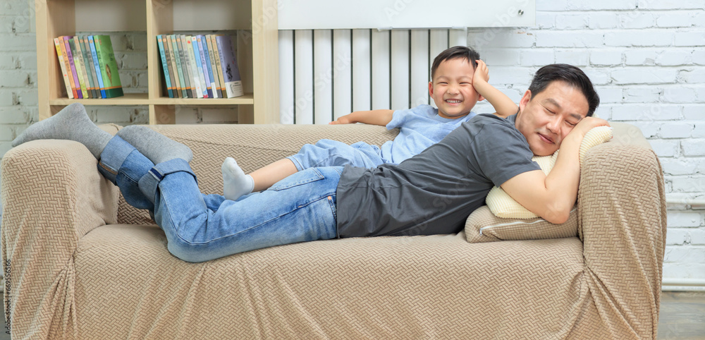 On the sofa, the intimate father and son lie together On the sofa, the intimate father and son lie together