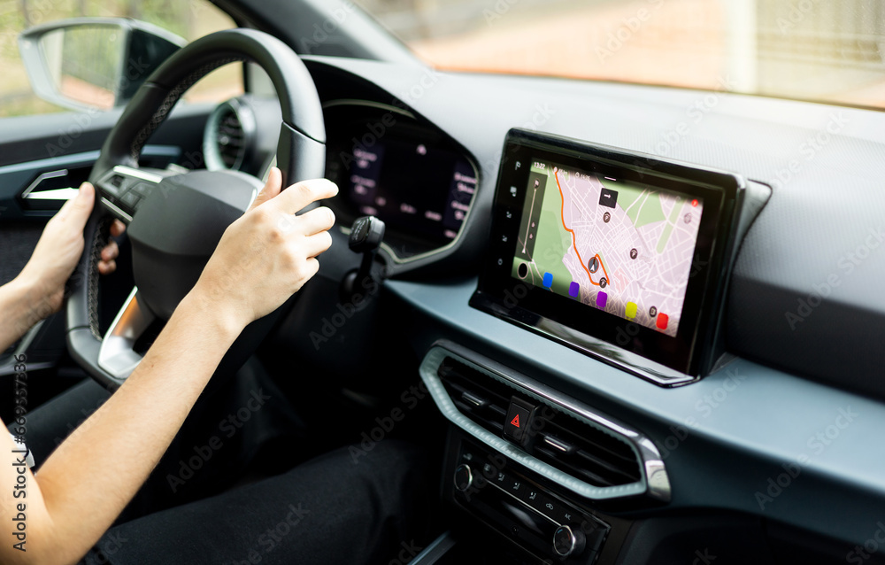 An unrecognizable person driving a car using the GPS on the digital display on the dashboard. Global positioning system. Application of the automatic navigation location system.
