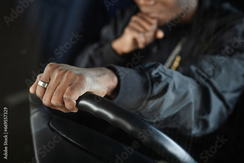 Focus on hand of young black man in stylish jacket on steer of car during drive to dance club for repetition or performance
