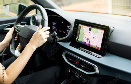An unrecognizable person driving a car using the GPS on the digital display on the dashboard. Global positioning system. Application of the automatic navigation location system.