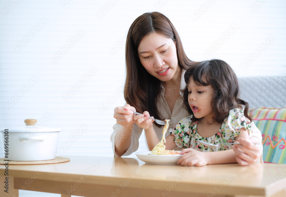 Cute little girl eat spaghetti as her mother be feeds her. Cute little girl eat spaghetti as her mother be feeds her.