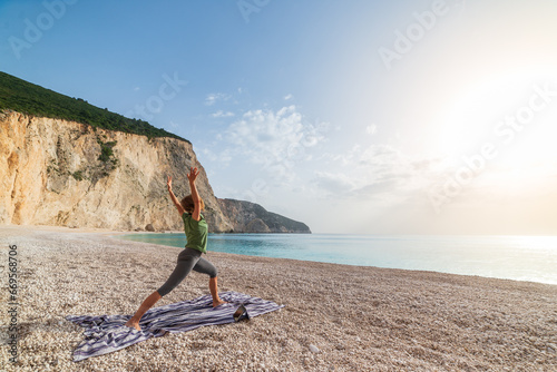 Obraz na płótnie Woman performing yoga exercises on a beautiful empty beach in Greece. Dramatic coastline scenic bay rocky cliffs in the Ionian islands. w salonie