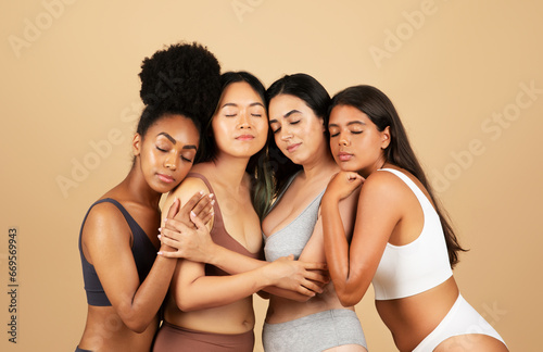 Diverse group of women in underwear, embracing on a beige background