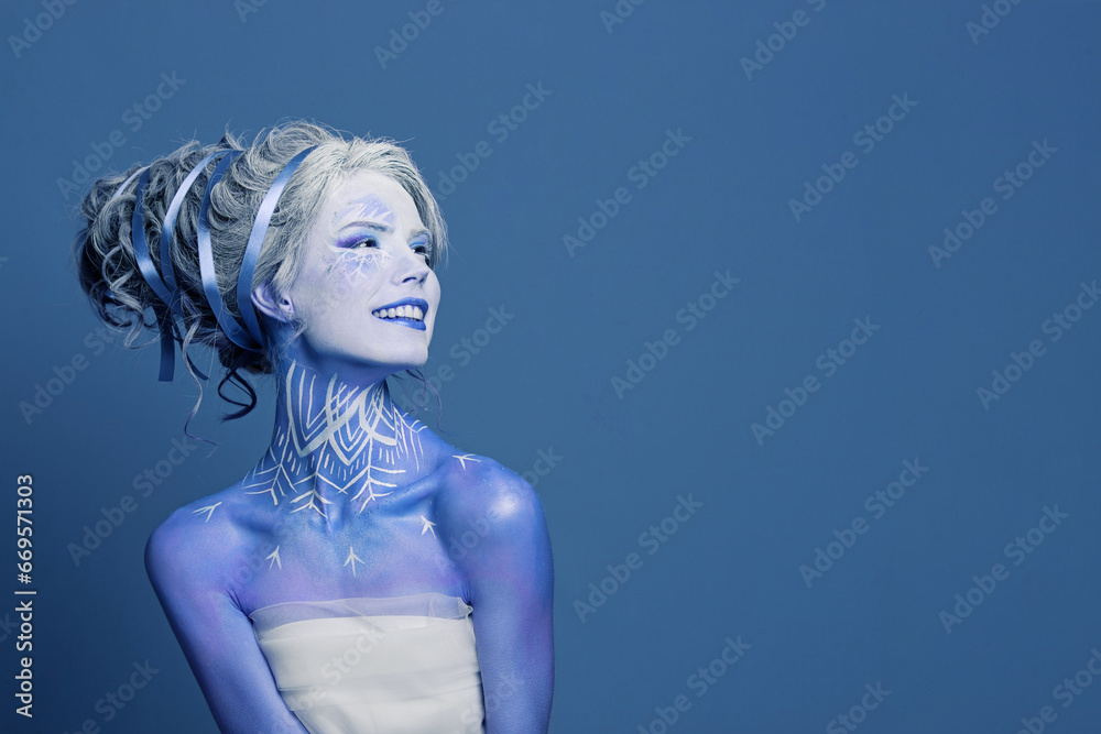 Happy smiling winter queen woman actress with stage makeup having fun on blue banner background. Halloween, carnival, performance and theater concept