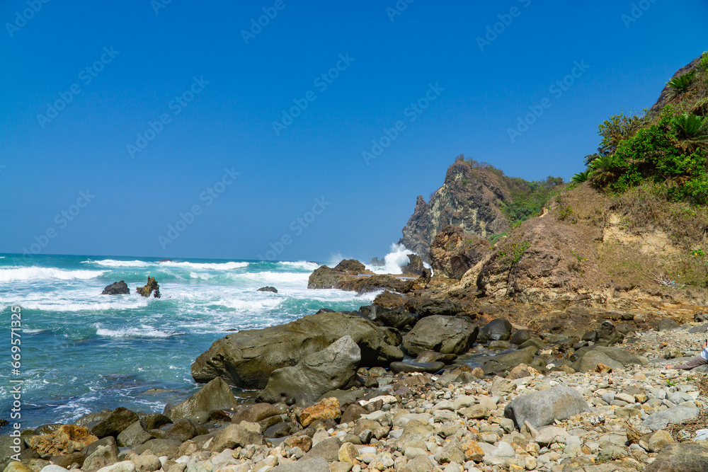 Rocky shoreline of Watu Lumbung Beach, Indonesia. Tidal waves hits the coral rock