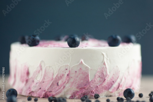 Bakery, candy shop concept. Close-up image of amazing bird cherry and blueberry cake with white and pirple topping. Natural light. Copy-space.  Indoor shot photo
