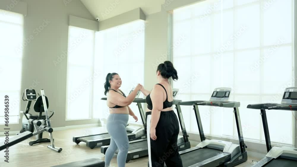 Two overweight Asian women, friends determined to exercise to lose weight, invited each other to run on the treadmill in the village club gym during their free time. Concept Lifestyle and exercise Two overweight Asian women, friends determined to exercise to lose weight, invited each other to run on the treadmill in the village club gym during their free time. Concept Lifestyle and exercise