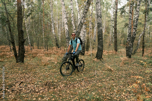 a cyclist with a backpack rides a mountain bike through the forest in autumn.Cross-country mountain biking