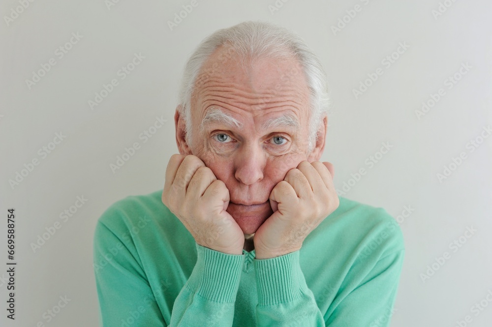 Facial portrait of a gray-haired elderly man with a pensive serious look close-up on a light background. Facial portrait of a gray-haired elderly man with a pensive serious look close-up on a light background.