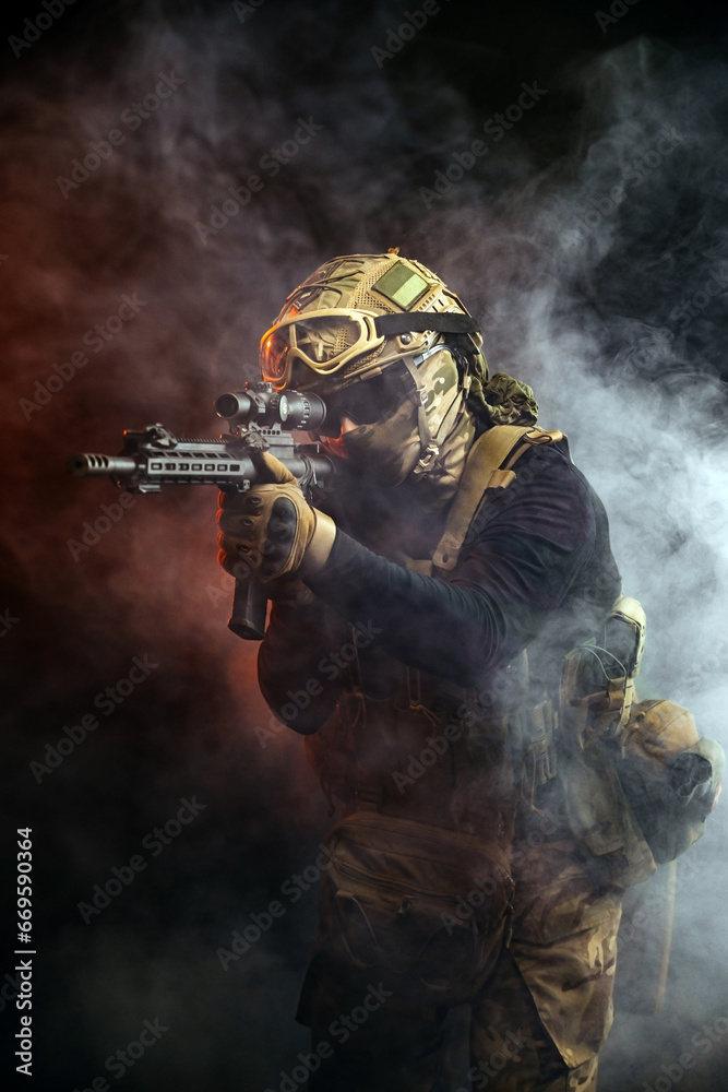 A soldier in combat gear with a weapon in his hands stands in battle formation among fire and smoke. The concept of military affairs. Computer games. The concept of war and combat. A soldier in combat gear with a weapon in his hands stands in battle formation among fire and smoke. The concept of military affairs. Computer games. The concept of war and combat.